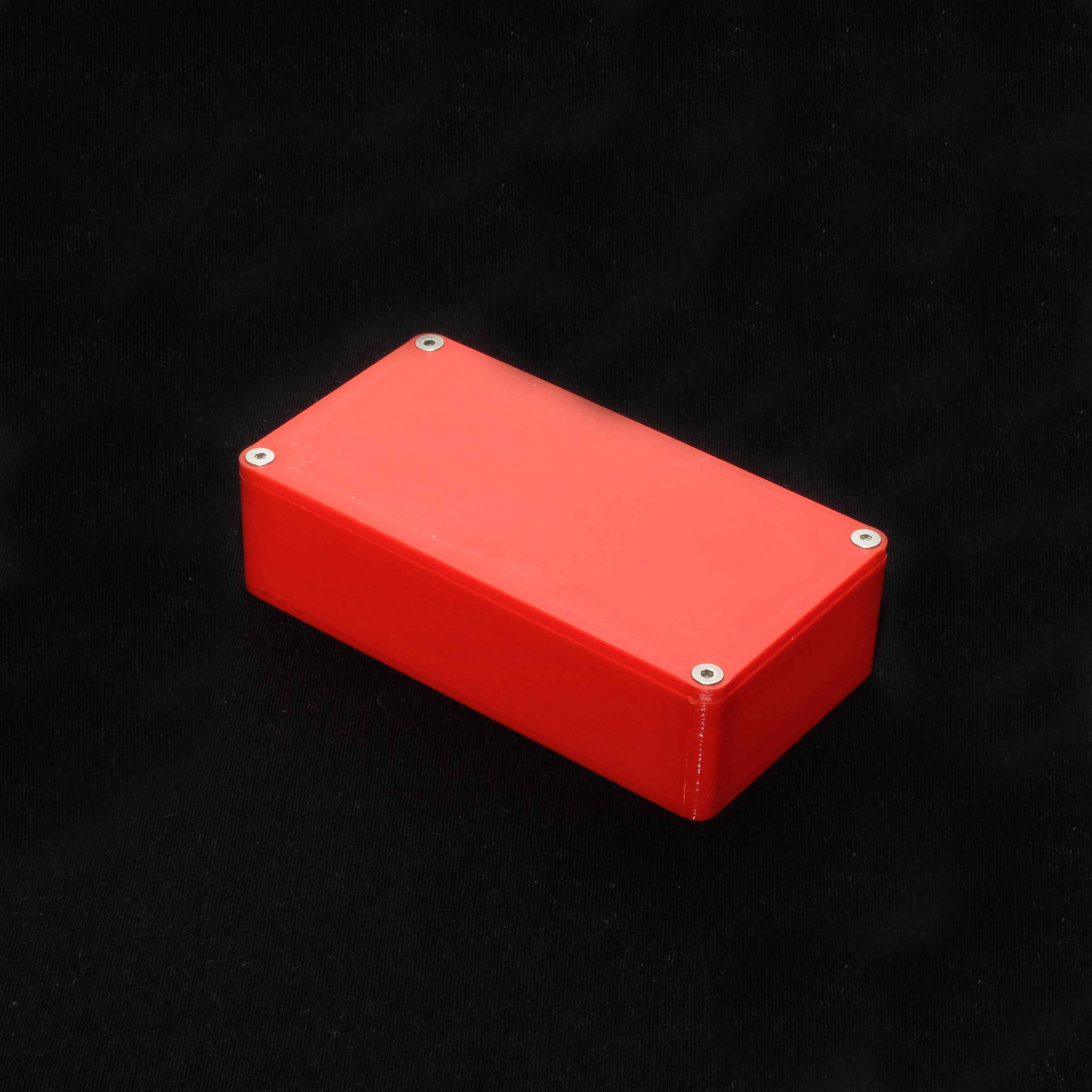 Small red enclosure showing lid and stainless steel screws