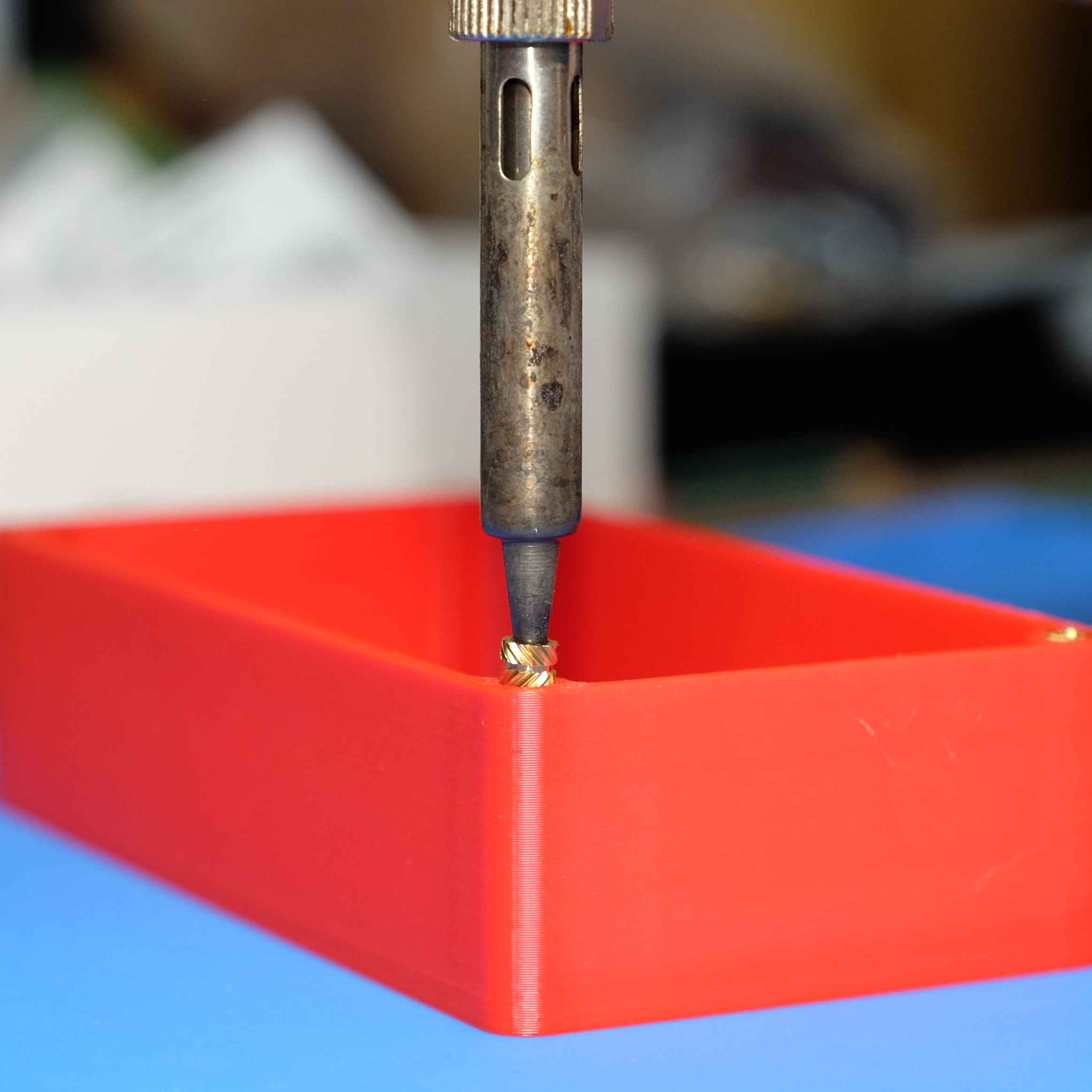 Inserting a brass thread into one corner of the red box with a soldering iron
